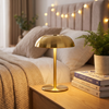 Gold mushroom cordless table lamp glowing on a bedside nightstand
