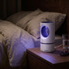 Nightfall mosquito trap glowing violet on a bedside table at night beside linen bedding